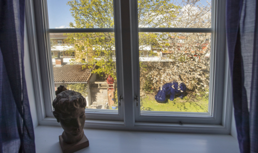 Utsikten från fönstret mot trädgården med ett magnoliaträd och en stor blå flodhäst.